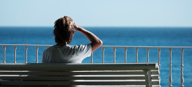 man looking out at the horizon by the sea.