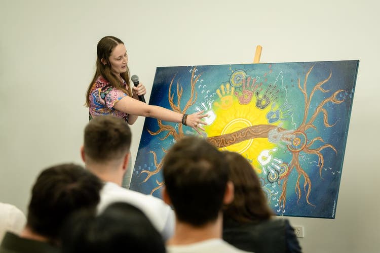 First Nations artist, Merinda Walters, points and speaks to her artwork, created to commemorate 150 years of BOQ, in front of Brisbane staff.
