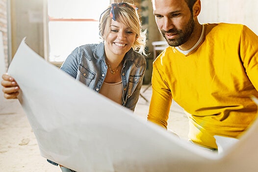 A couple look at construction plans in their fixer upper home