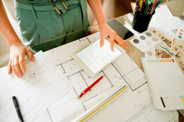 construction plans lay out on a table with a person's hands holding them