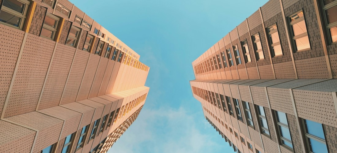 two buildings from below, with blue sky peeking out.