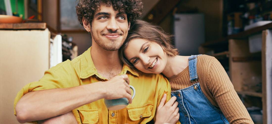 couple sitting on doorstep drinking coffee smiling