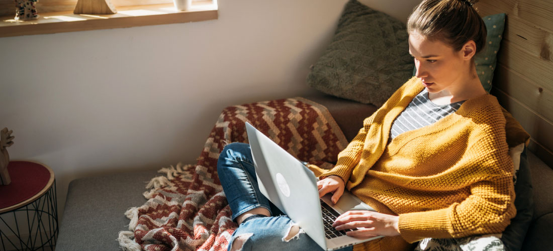 woman sitting on couch with laptop - money mistakes blog