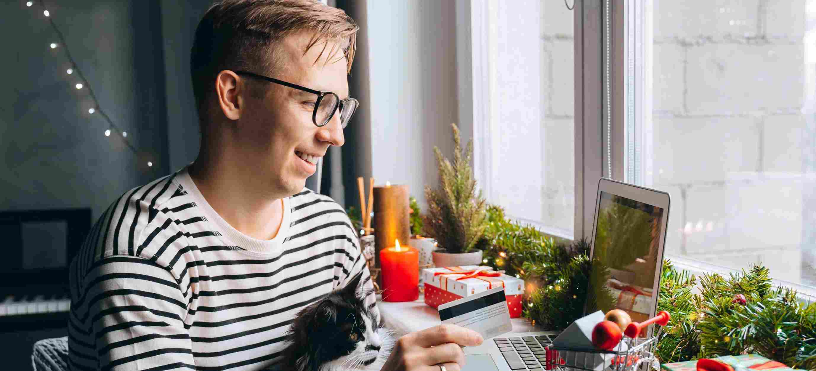 Man with cat online shopping with credit card at Christmas time