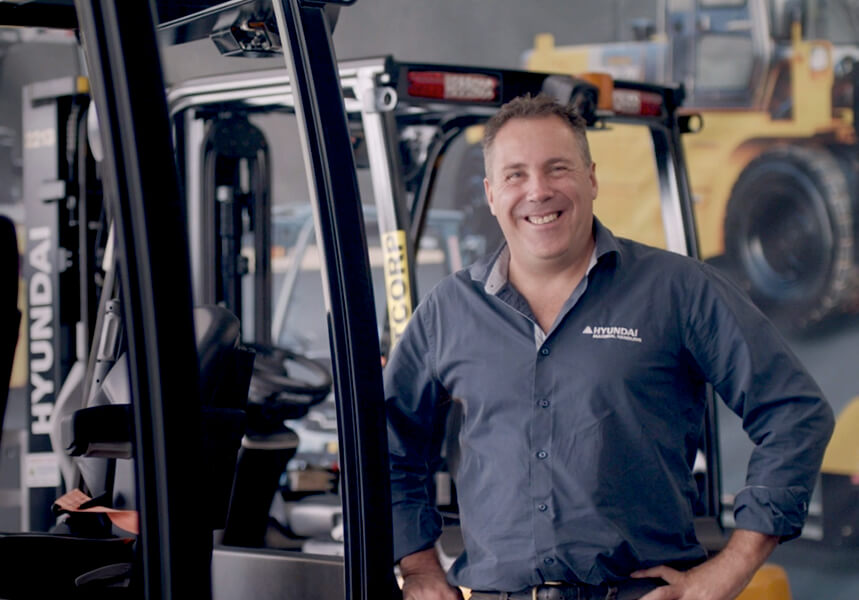 Smiling man next to a Hyundai forklift