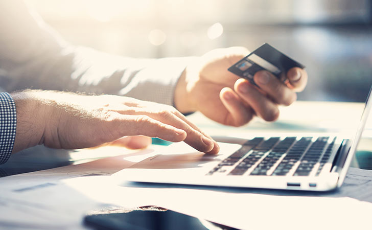 person using their business debit card with their laptop