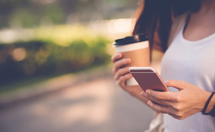 Woman texting with a coffee